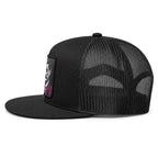 A black trucker-style baseball cap with a black mesh back and a black fabric brim, featuring gold contrast stitching along the edge of the brim and a small white logo patch on the side.
