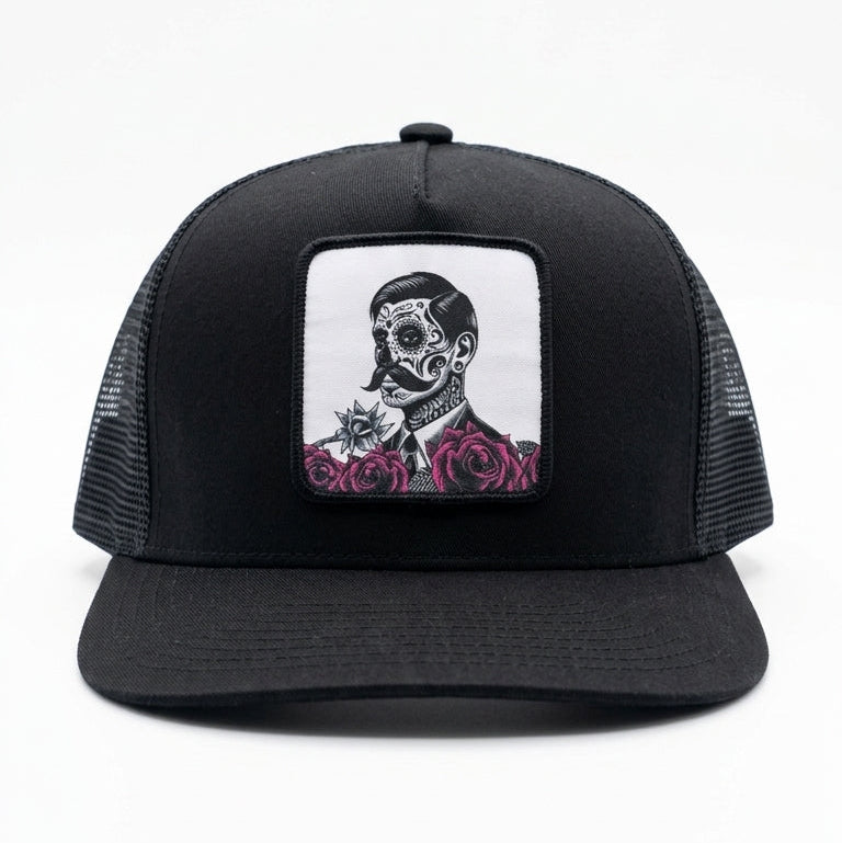 Black trucker cap with a skull and roses design on a white background