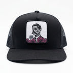 Black trucker cap with a skull and roses design on a white background